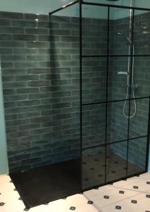 La salle de bains est pourvue d'une douche en verre et d'un mur en briques. dans l'établissement Le Gite de Tassigny, à Meursault