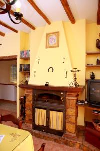 a living room with a stone fireplace with a tv at La Choza De Mamuyo in Montefrío