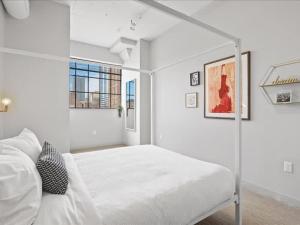 a white bedroom with a bed and two windows at CozySuites Modern 2BR, Downtown Pittsburgh in Pittsburgh