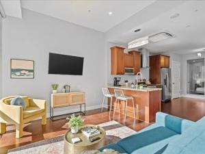 a kitchen and living room with a blue couch and a kitchen at CozySuites Modern 1BR, PPG Paints Arena, Pitts in Pittsburgh