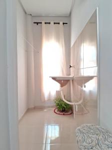 Habitación blanca con lavabo y ventana en Flat ideal para familia e grupos de amigos proximo ao aeroporto e rodoviária, en Palmas