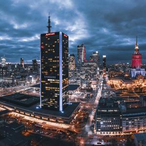 una città illuminata di notte con un edificio alto di Warsaw Marriott Hotel a Varsavia