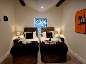 a bedroom with two beds and two ottomans at The Hamilton luxury holiday let's- Holly Barn in Scorton