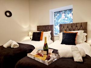 2 camas con una botella de vino y una bandeja de comida en The Hamilton luxury holiday let's- Holly Barn, en Scorton