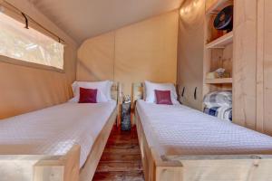 two twin beds in a small room withermottermottermott at 12 Fires Luxury Glamping #3 in Johnson City