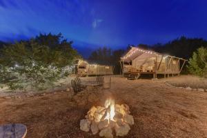 a campfire in a yard with a yurt and a tent at Tent #3 - Glamping on a Winery in Texas Hill Country in Johnson City