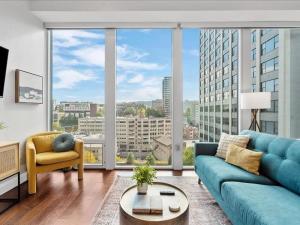 a living room with a blue couch and large windows at CozySuites 1BR, PPG Paints Arena, Pitts in Pittsburgh