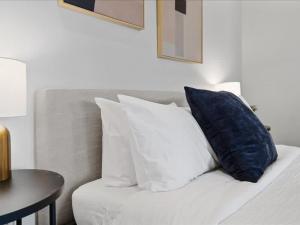 a white bed with a blue pillow and a table at CozySuites 1BR, PPG Paints Arena, Pitts in Pittsburgh