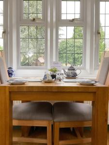 uma mesa de jantar com 2 cadeiras e 2 janelas em Southlands B&B em Bourton on the Water