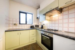 een keuken met witte kasten en een fornuis met oven bij Amazing 2Bed in Canary Wharf in Londen