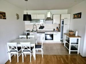 a kitchen with white cabinets and a table and chairs at THE BIG SPACE - Apartmaji PANONIA in Moravske Toplice