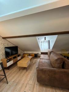 een woonkamer met een bank en een tv bij HYPERCENTRE - Duplex de charme in Blois