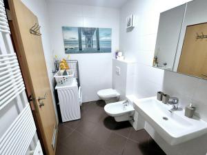 a white bathroom with a toilet and a sink at THE BIG SPACE - Apartmaji PANONIA in Moravske Toplice