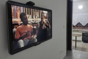 a television with a picture of a man and a woman at Casa Agradável, Arejada, Espaçosa, Perto de Tudo in Londrina