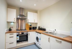 a kitchen with white cabinets and a washer and dryer at Apple Tree in Redhill