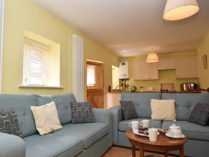 uma sala de estar com um sofá azul e uma mesa em 2 Bed in Wroxham 29570 em Worstead
