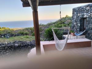 a hammock on a house with a view of the ocean at Dammusielenas in Pantelleria