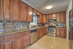 a kitchen with wooden cabinets and stainless steel appliances at Backyard Oasis! 2 mi to Pier with Pool, Patio Bar & Putting Green in Safety Harbor