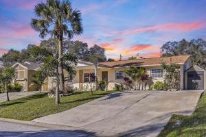 a house with palm trees in front of a driveway at Backyard Oasis! 2 mi to Pier with Pool, Patio Bar & Putting Green in Safety Harbor