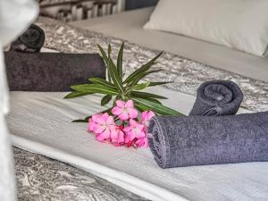 a bed with purple towels and pink flowers on it at Tenerife Paradise Anna Studio in Adeje
