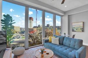 a living room with a blue couch and a large window at TWO Posh CozySuites, PPG Paints Arena, Pitts in Pittsburgh