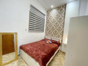 ein kleines Schlafzimmer mit einem Bett mit einer roten Decke in der Unterkunft Appartement de Luxe in Kenitra