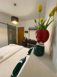 a vase with flowers sitting on a table next to a bed at S'accabbadora Guest House in Alghero