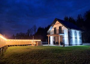une maison avec des lumières sur son côté la nuit dans l'établissement Jelonkowo, à Brenna