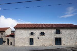 un edificio de piedra con ventanas y techo rojo en Casa da Saia Grande - Recantos d'Almerinda, 