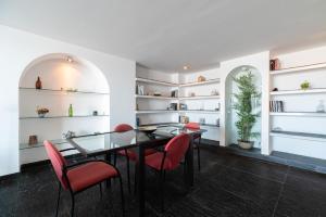 a dining room with a glass table and red chairs at El Balcón de Samil in Vigo
