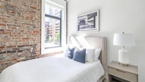 sypialnia z białym łóżkiem z ceglaną ścianą w obiekcie Landing - Modern Apartment with Amazing Amenities (ID5790X40) w mieście Birmingham