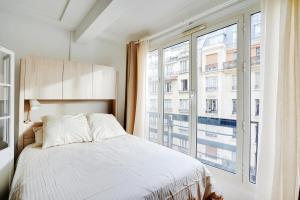 a bedroom with a bed and a large window at Parisian Charm Porte Maillot in Paris