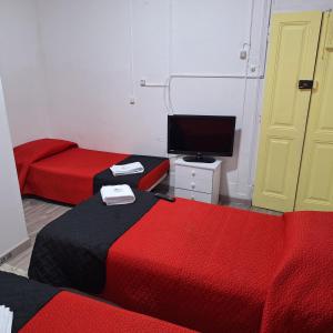 a room with two beds and a flat screen tv at Hostal Africa Do Sul in Lisbon