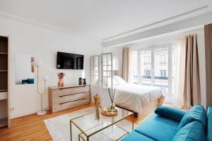 a living room with a bed and a blue couch at Parisian Charm Porte Maillot in Paris