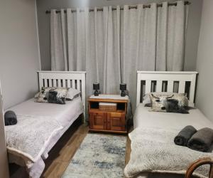 Duas camas individuais num quarto com cortinas em Lekaja em Oudtshoorn