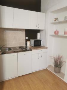 kuchnia z białymi szafkami i mikrofalówką w obiekcie Apartment Matovina w mieście Zadar