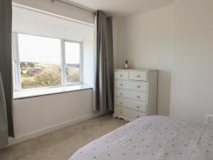 1 dormitorio con cama, ventana y vestidor en Haulfryn en Holyhead