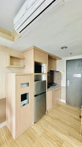 a kitchen with wooden cabinets and a stainless steel refrigerator at Tamansari Hive Cawang by Villaloka in Jakarta