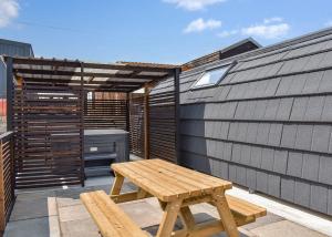 un patio con banco de madera y bañera de hidromasaje en Hill Farm Retreat en Wangford
