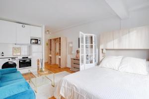 a white bedroom with a bed and a blue couch at Parisian Charm Porte Maillot in Paris