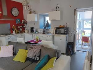 ein Wohnzimmer mit einem Sofa und einer Küche in der Unterkunft Les volets bleus in Prémian