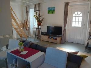 uma sala de estar com um sofá e uma televisão em Les volets bleus em Prémian