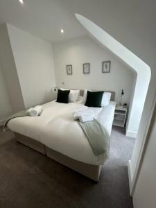 een slaapkamer met een groot wit bed met groene kussens bij churchward house flat 4 in Chertsey