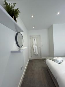 a white room with a mirror and a bed at churchward house flat 4 in Chertsey