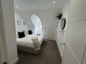 a white bedroom with a bed and an arched doorway at churchward house flat 4 in Chertsey