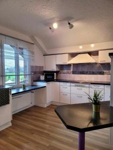 a kitchen with white cabinets and a table in it at Chalet Nature Park "Apartment Spiez" in Thun