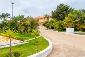 Belas的住宿－Decifer Sport Resort，一条有棕榈树的道路,一座黄色的房子