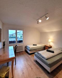 Zimmer mit 2 Betten, einem Tisch und einem Schreibtisch in der Unterkunft Chalet Nature Park "Apartment Spiez" in Thun
