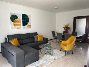 a living room with a couch and a table and chairs at Populo Beach Villa, Walk to Beach, Air Conditioning and Heating, near Ponta Delgada in Livramento