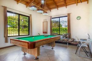 uma mesa de bilhar numa sala de estar com janelas em Villa Roble Alto em Guanacaste